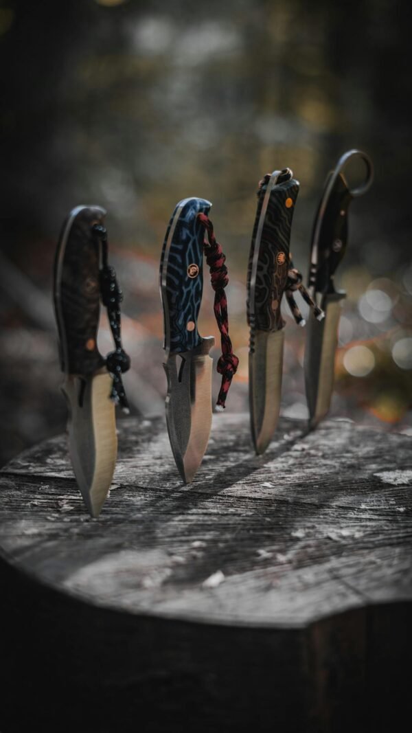 Four sharp knives with patterned handles displayed vertically on a wooden surface outdoors.