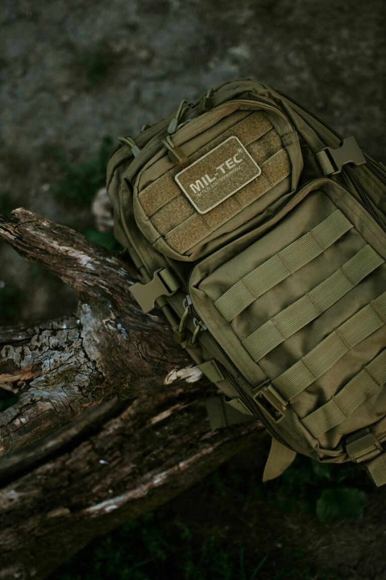 Olive green MIL-TEC backpack resting on a tree branch in a rural outdoor setting, emphasizing travel and adventure.