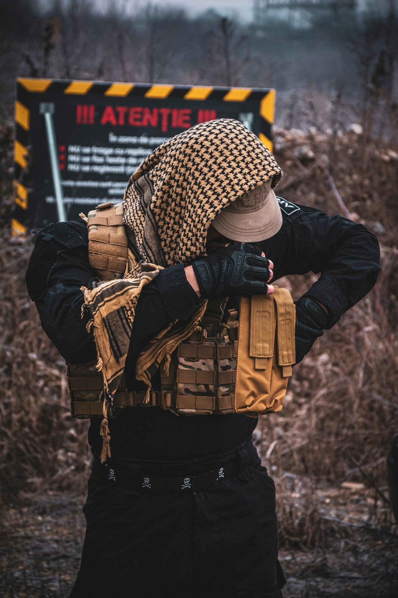 Tactical operator adjusting gear in an outdoor setting, wearing camouflage and tactical vest.